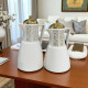 A set of tea and coffee thermoses in several colors with prominent golden decorations and a golden lid.