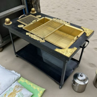 Charcoal grill, black iron barbecue made of metal with gold handles.